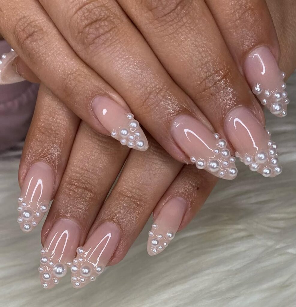 long almond nails with nude base and white pearl embellishments