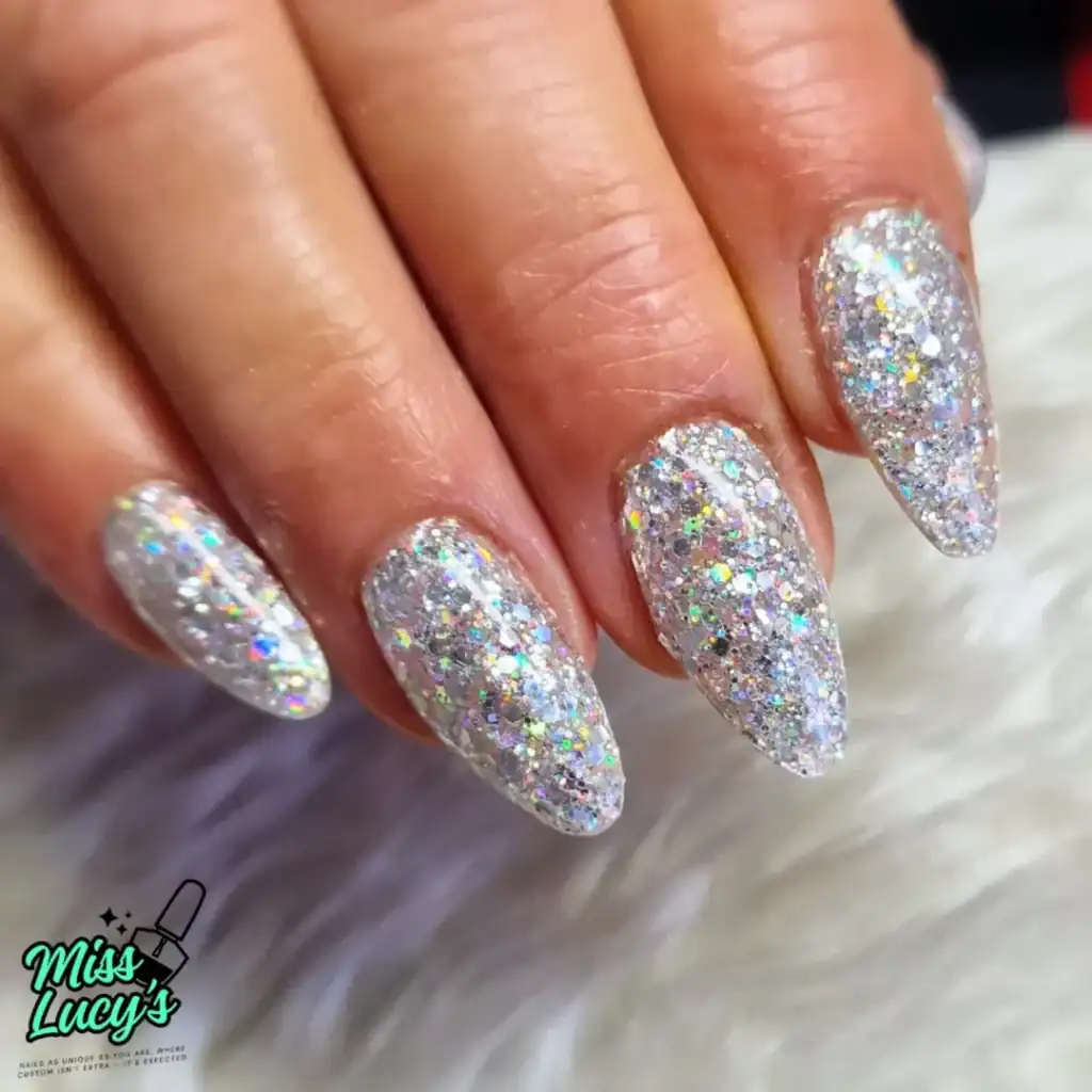 hand with long almond-shaped nails covered in chunky holographic silver glitter polish.