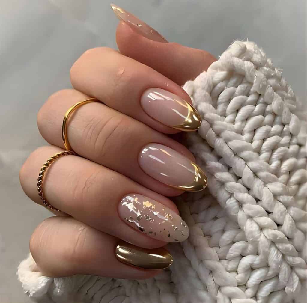 hand holding white chunky knitted sweater with nude and gold foil accent nails.