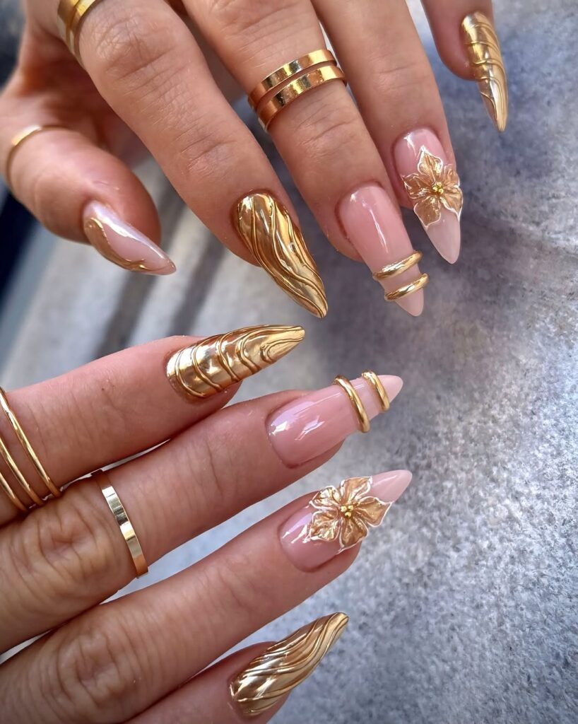 hand wearing gold rings and long almond nails with 3D gold accents and foil tips.