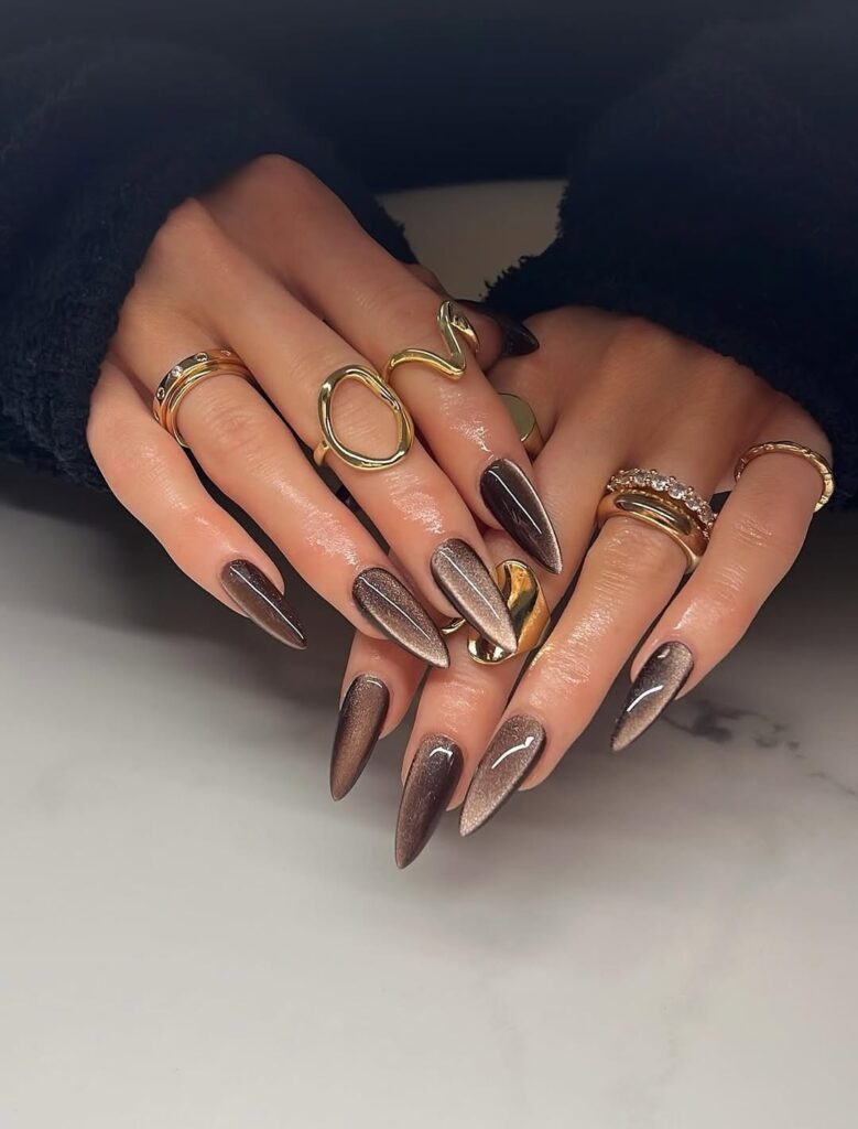almond-shaped brown cat eye nails with golden magnetic shimmer and gold rings