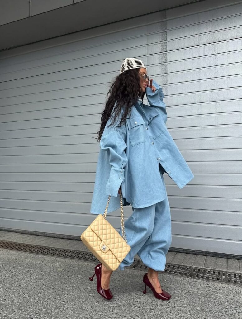 woman in y2k fashion wearing an oversized denim shirt, matching pants, and burgundy heels