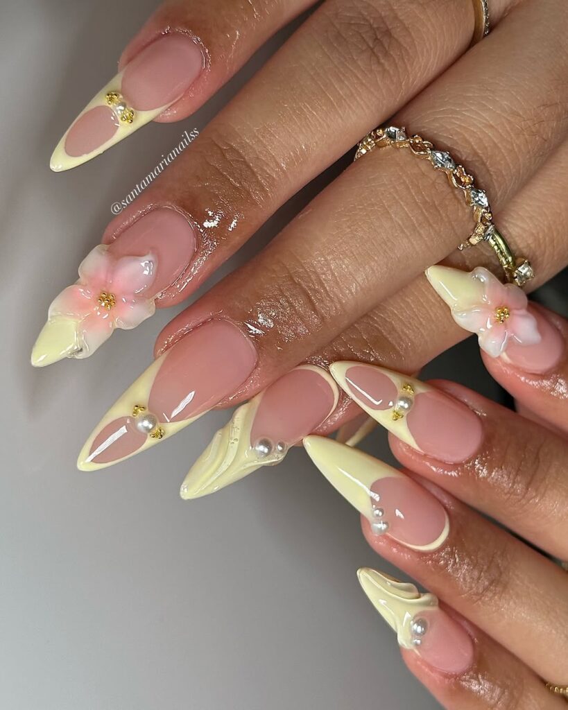 long almond nails with pale yellow french tips, 3d pink flowers, and pearl accents
