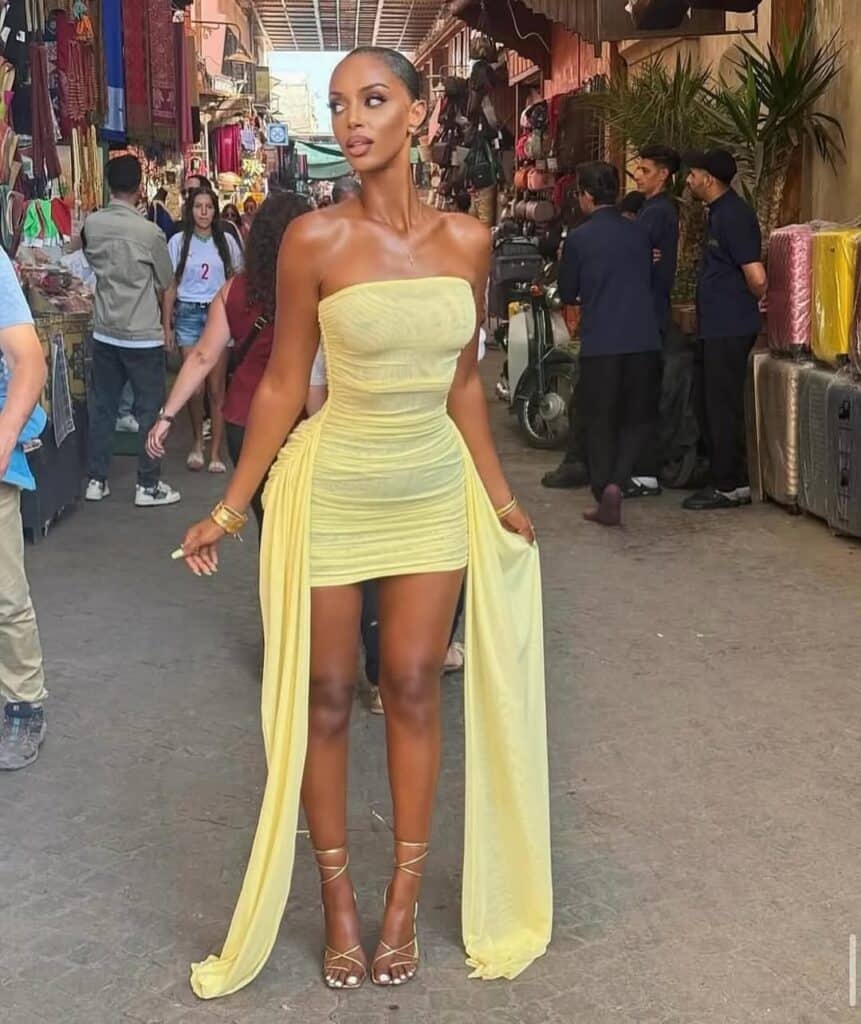 woman in a yellow strapless mini dress with long side drapes walking through an outdoor market