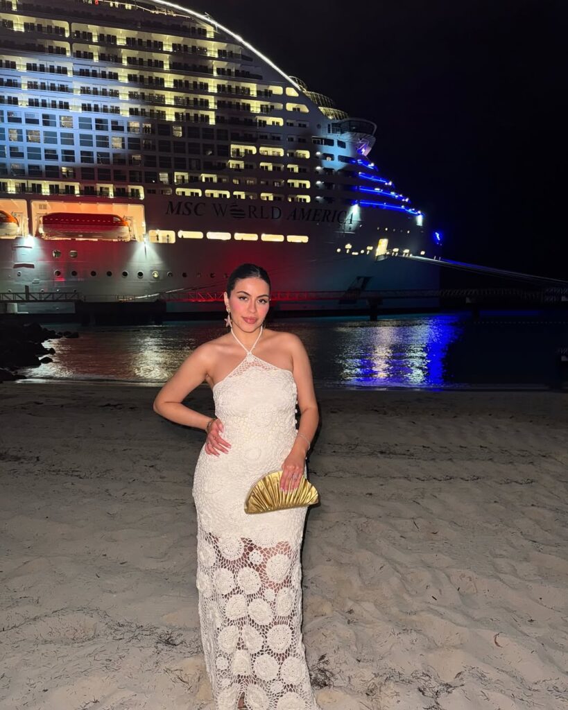 woman in a white crochet halter maxi dress on a beach at night