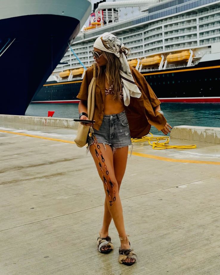woman wearing headscarf and brown shirt with denim shorts walking at a cruise port