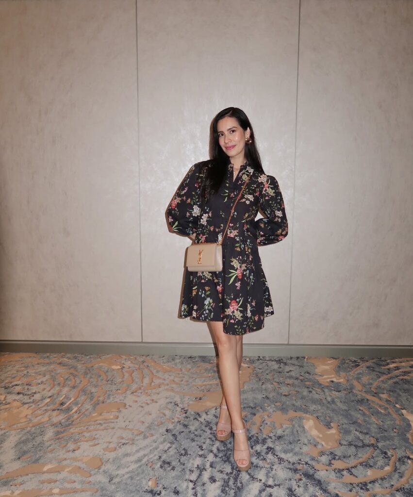 woman in a dark floral puff sleeve mini dress standing in a cruise ship hallway