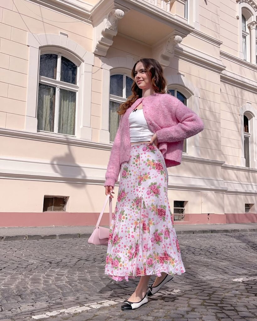 woman in pink fuzzy cardigan and floral midi skirt with ballet flats on cobblestone street