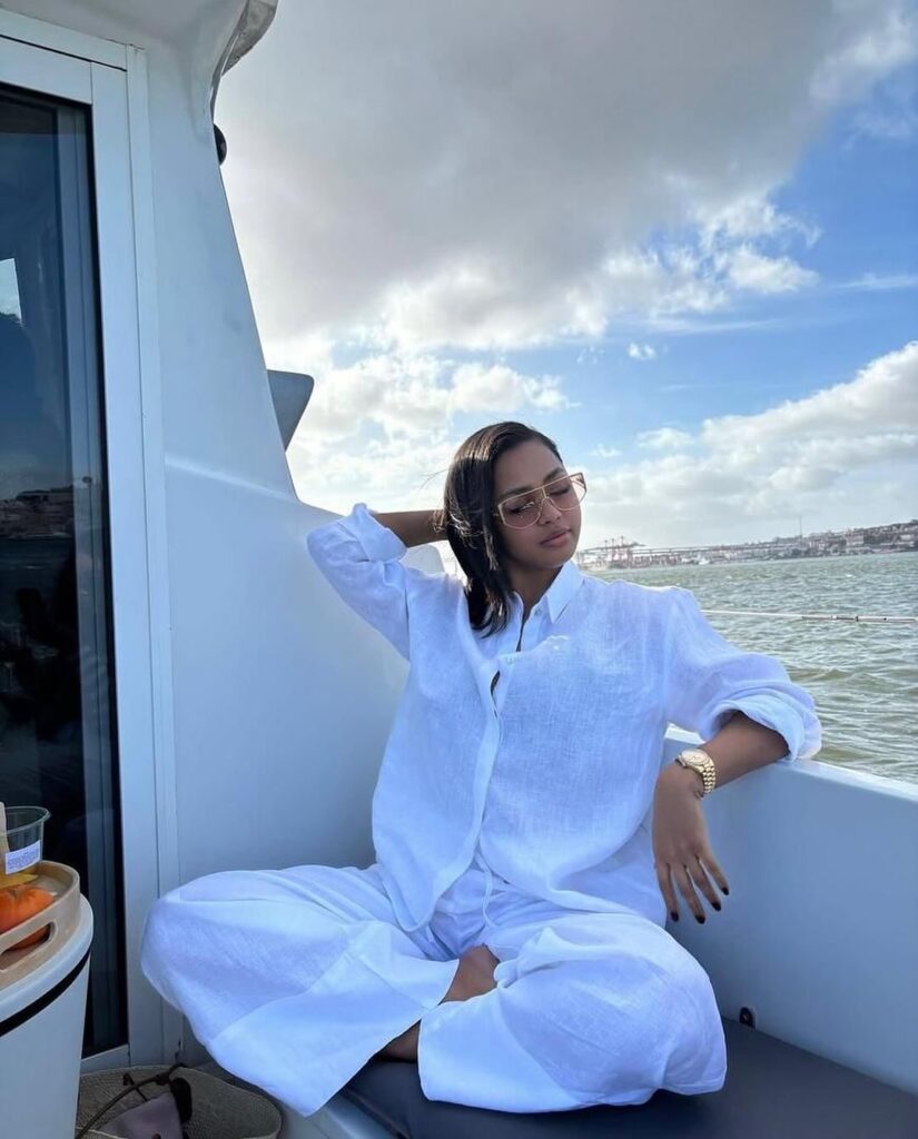 woman wearing a white two piece linen outfit while sitting on a boat deck
