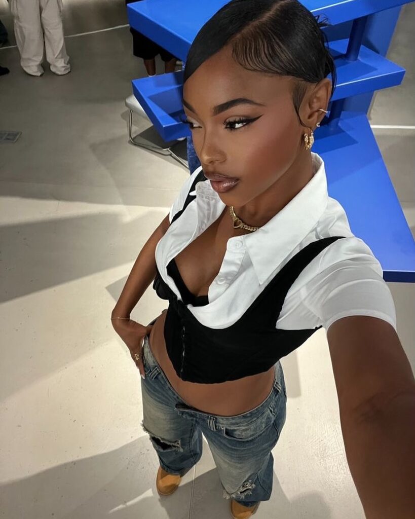 woman in y2k fashion wearing a white collared shirt, black corset, and distressed low-rise jeans