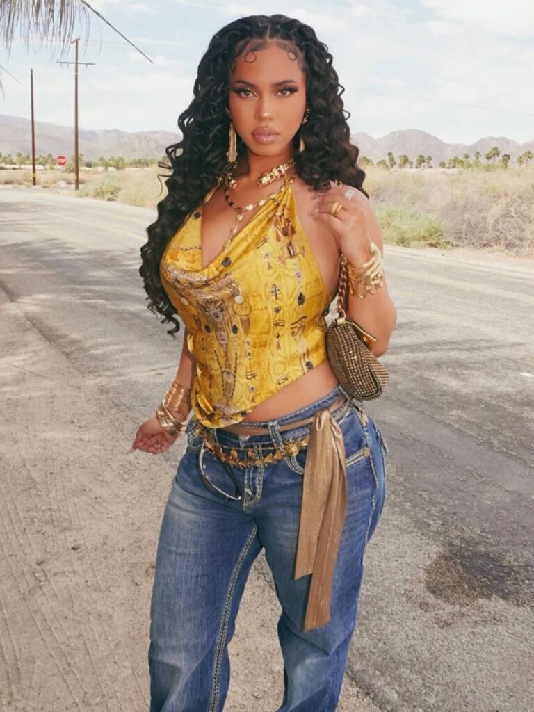 woman in y2k fashion wearing a yellow halter top, blue jeans, and gold accessories