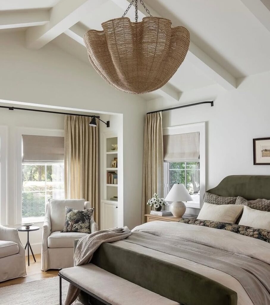 cozy bedroom with a large woven pendant light, green velvet headboard, and neutral bedding layers.