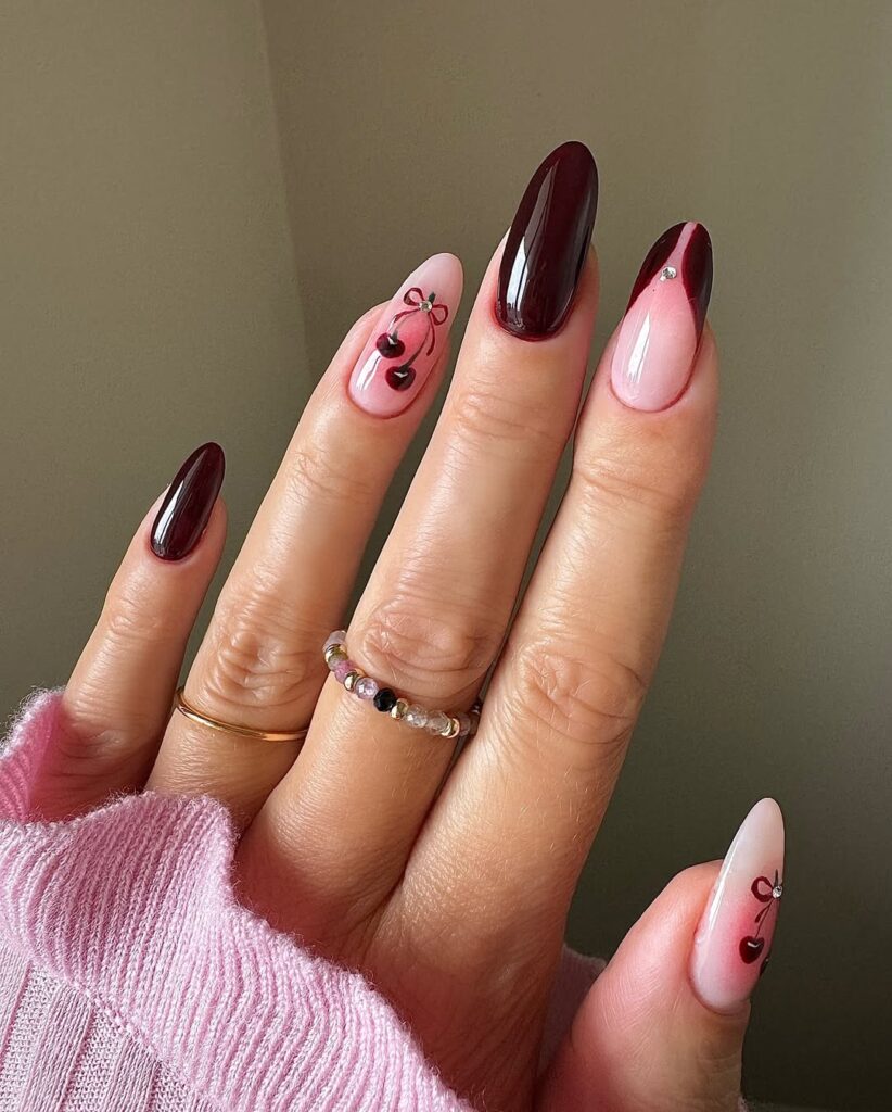 long almond burgundy nails with cherry art red bows and a pink accent nail