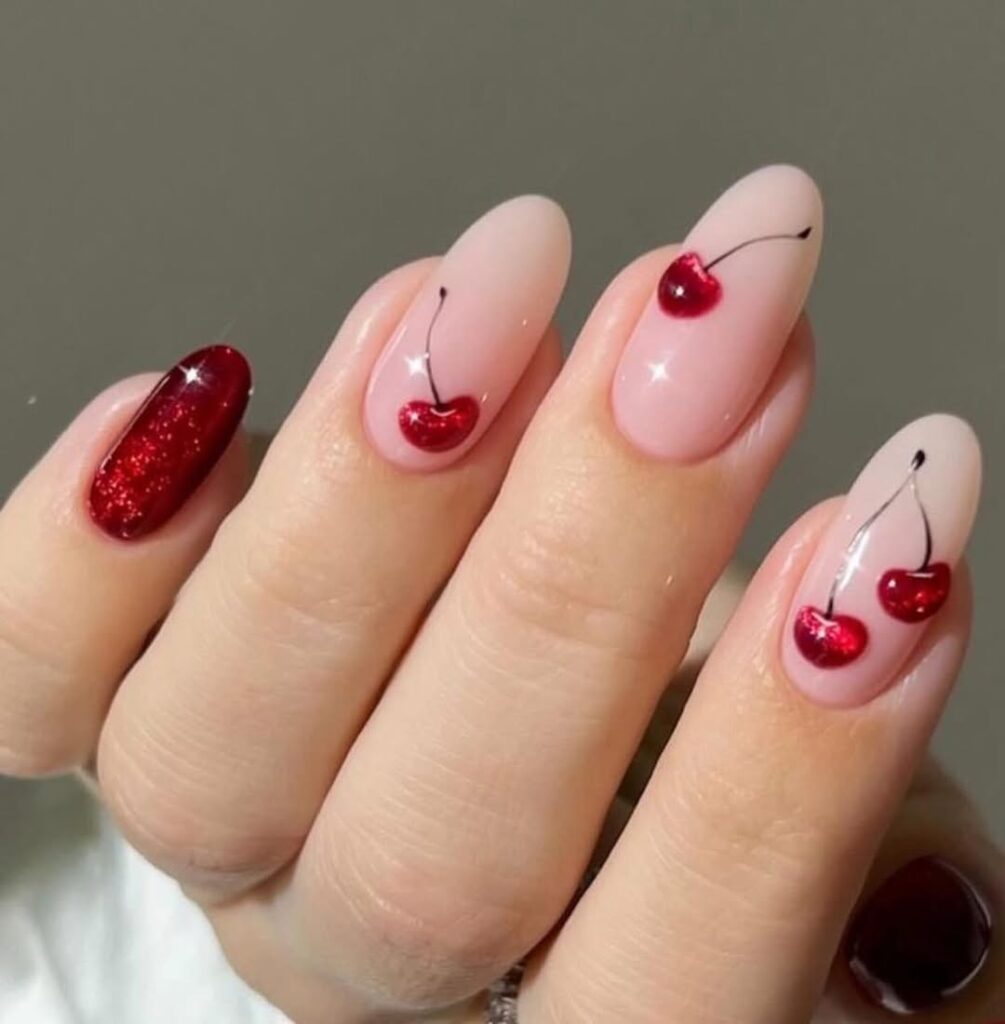 short oval nude nails with sparkly red cherry art and a red glitter accent nail