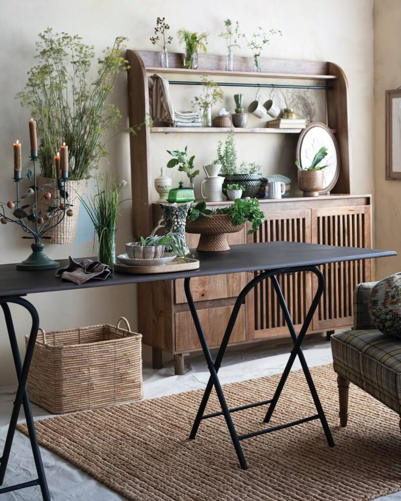 rustic wooden hutch and black folding table styled with fresh green plants and woven baskets.