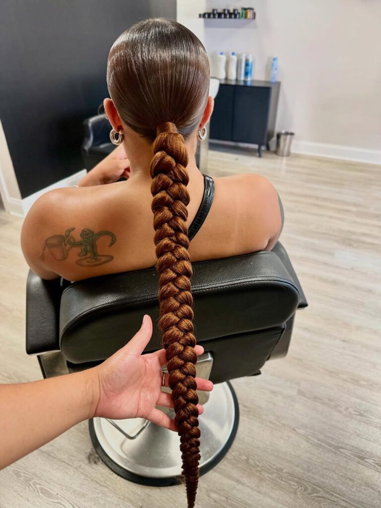 back view of a sleek low ponytail with a thick copper brown braid