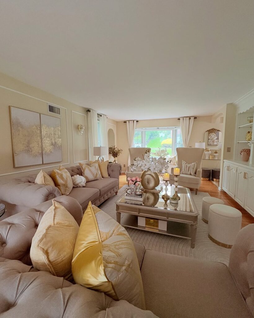 elegant living room with a tufted sofa, gold accents, and a mirrored coffee table display.
