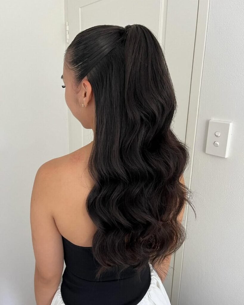 back view of a woman with long dark wavy hair in a high ponytail