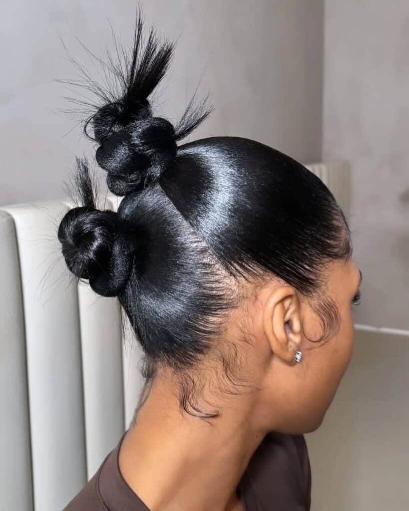 sleek black hair styled in two stacked buns with laid edges and silver earrings
