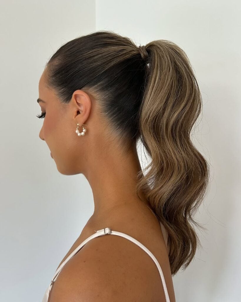 side profile of a woman with a sleek high ponytail and wavy blonde hair
