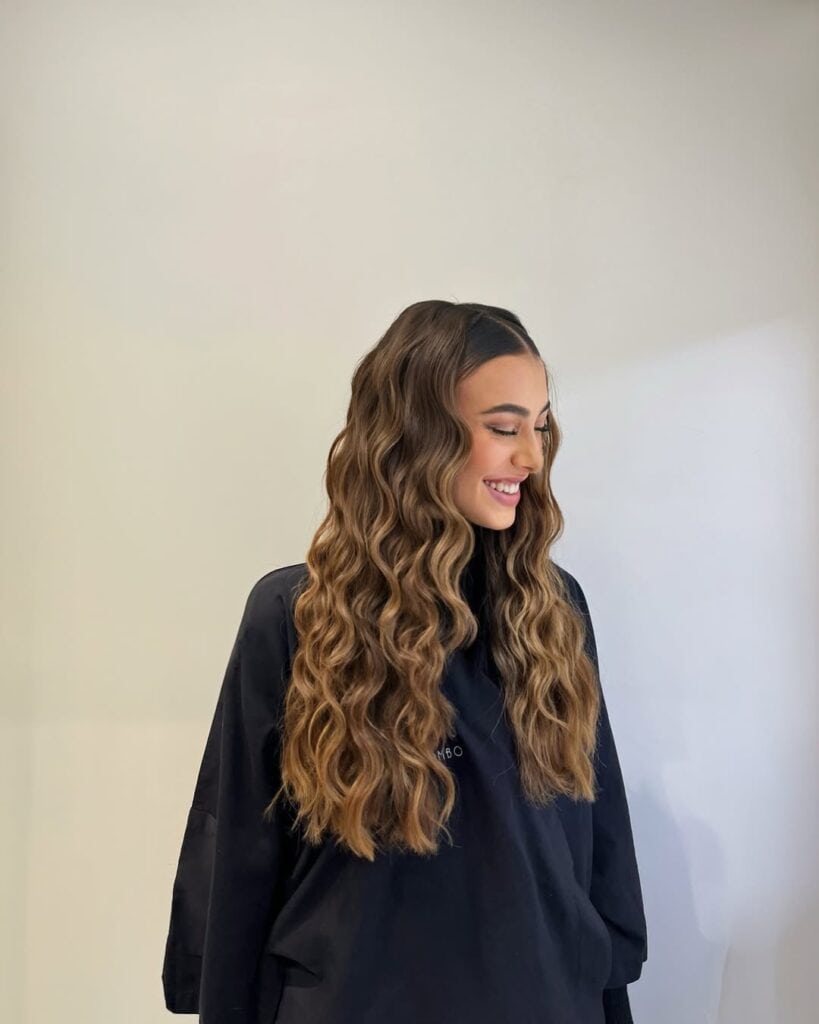 smiling woman with long brown hair styled in voluminous deep waves