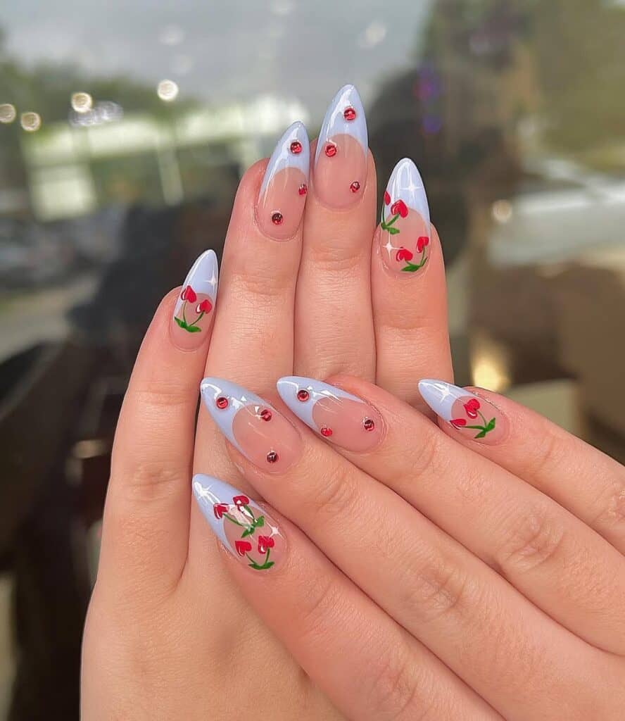 almond nails with light blue french tips red rhinestones and cherry nail art