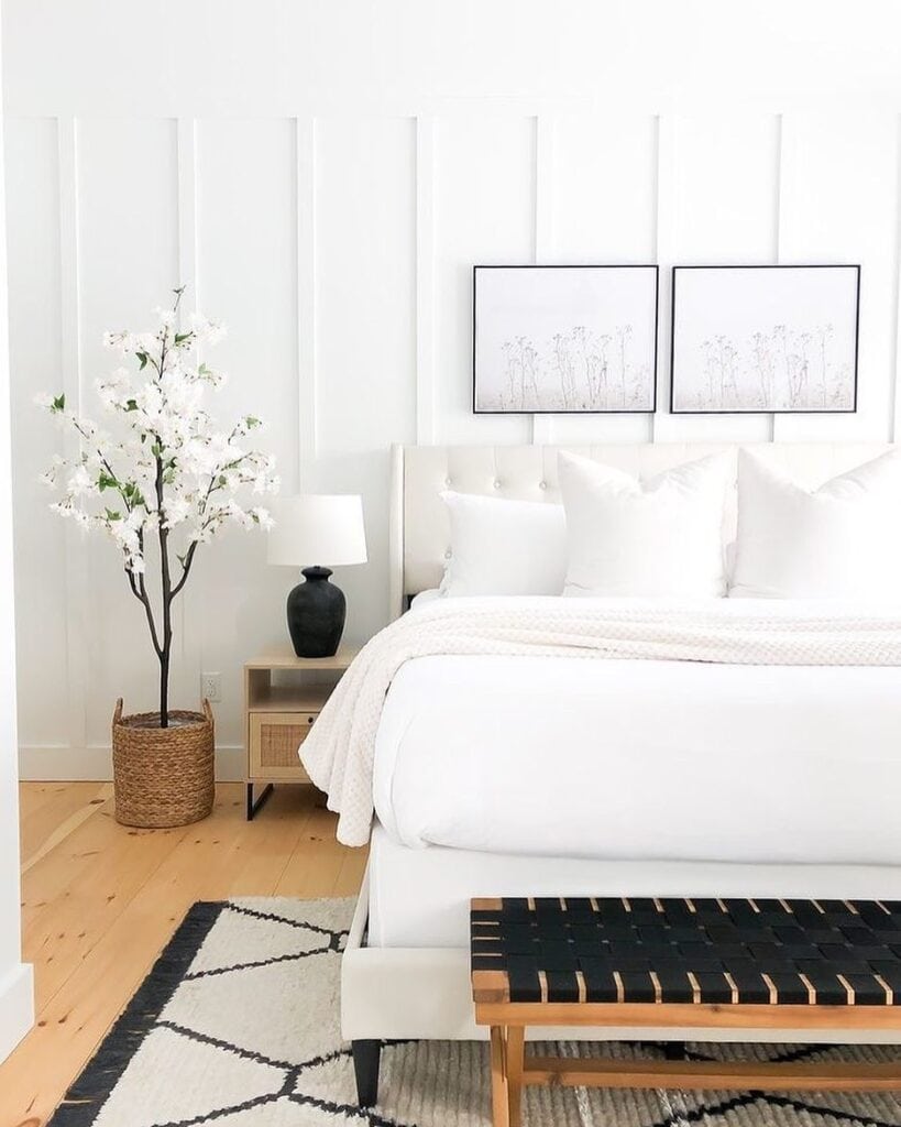 minimalist white bedroom with a cherry blossom tree and framed botanical wall art.