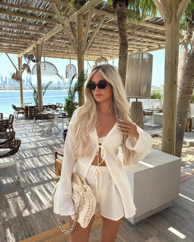 woman in cream textured two-piece set and sunglasses at an outdoor beach club