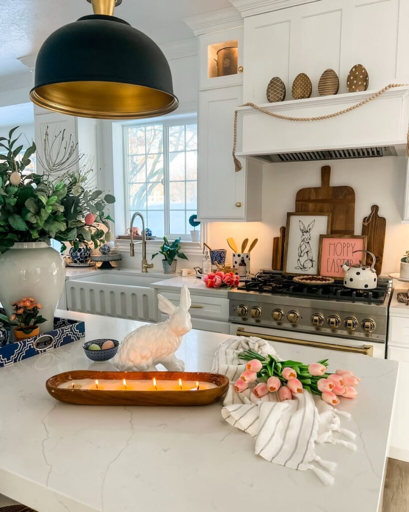 white kitchen island decorated for easter with pink tulips, a ceramic bunny, and lit candles.