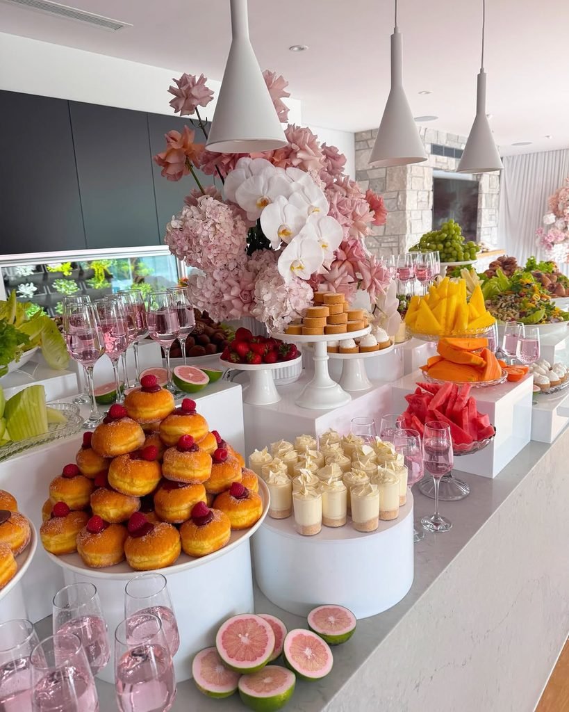 luxury bridal shower brunch buffet with pink flowers and assorted pastries.