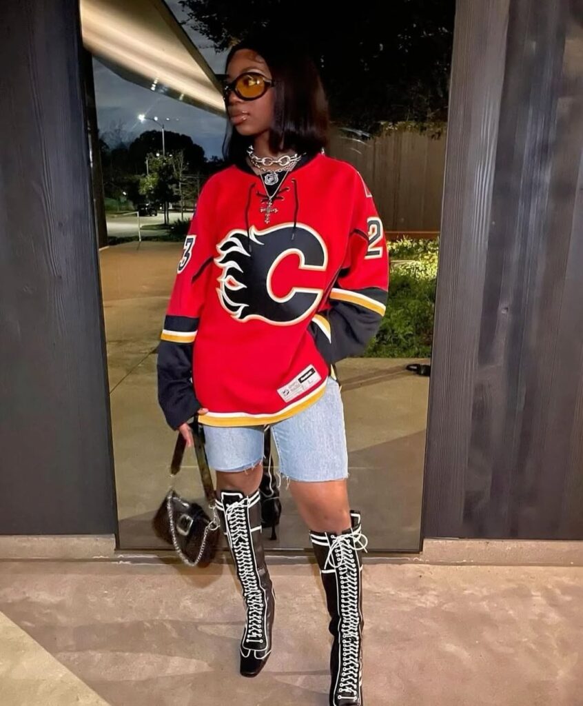 person wearing oversized red calgary flames jersey and tall lace up boots outdoors