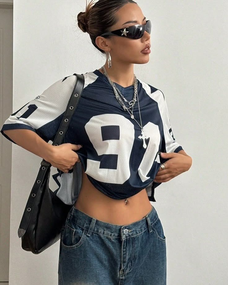 Woman in cropped blue and white jersey and baggy jeans wearing silver jewelry