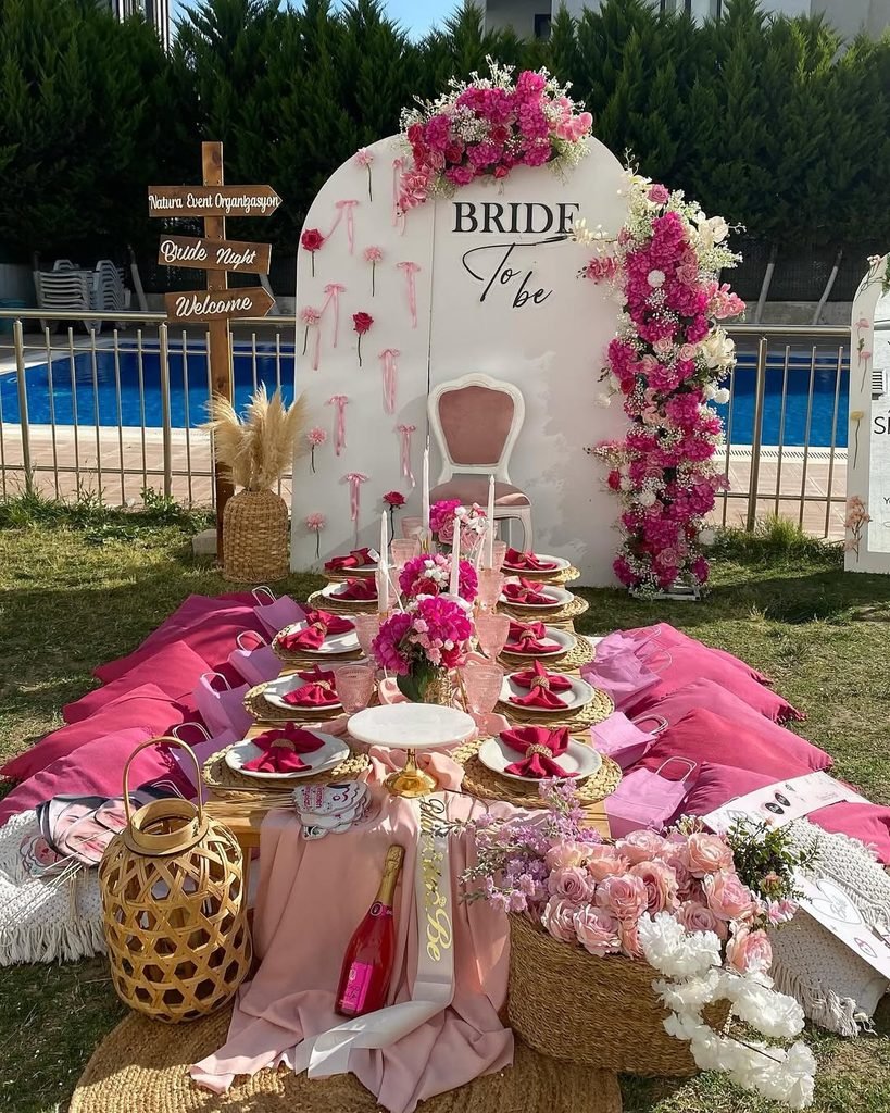 pink floral bridal shower decor with floor seating next to a pool.