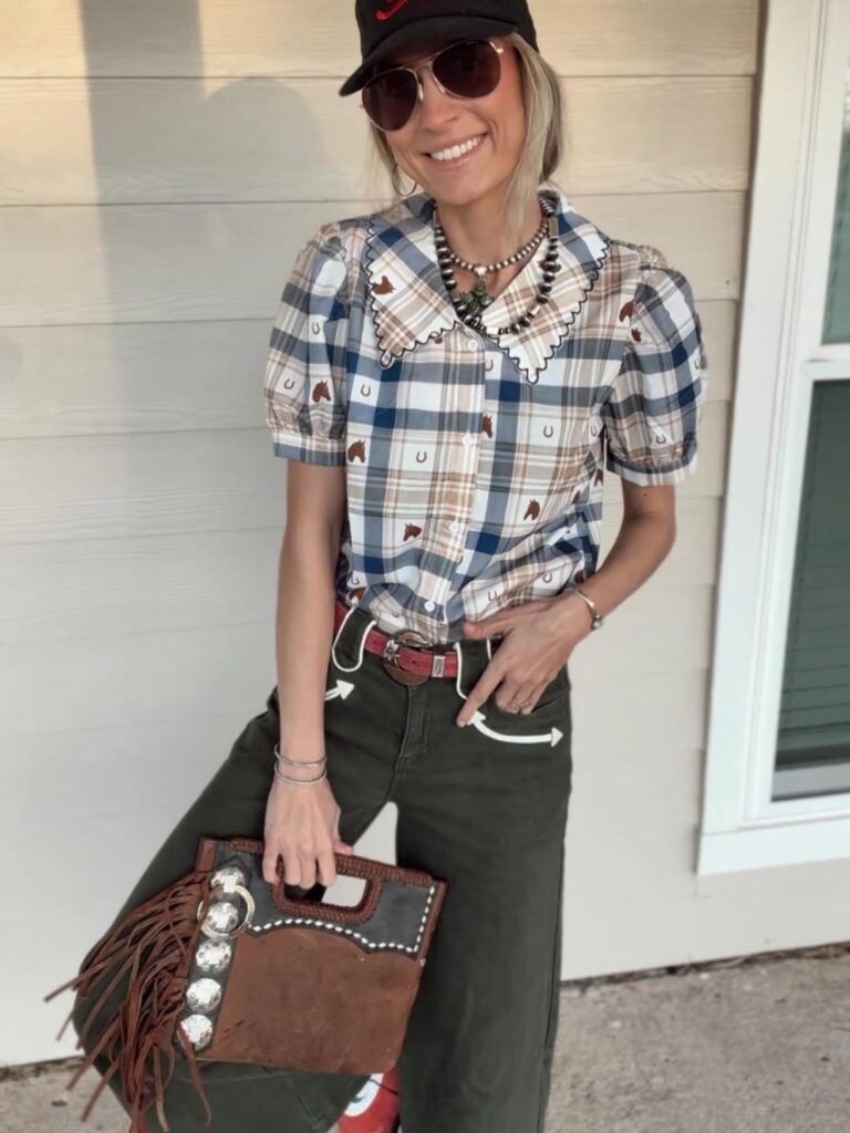 woman in a plaid horse print shirt holding a brown fringe leather western purse