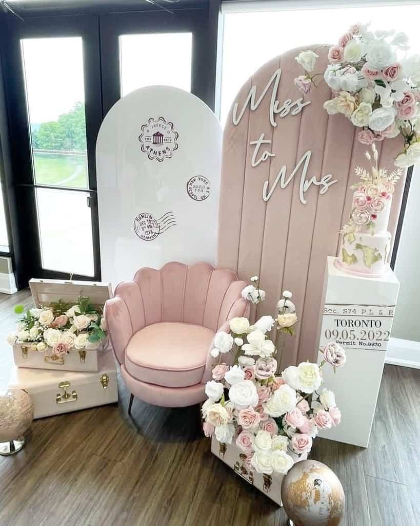 travel themed bridal shower decor with pink shell chair and floral suitcases.