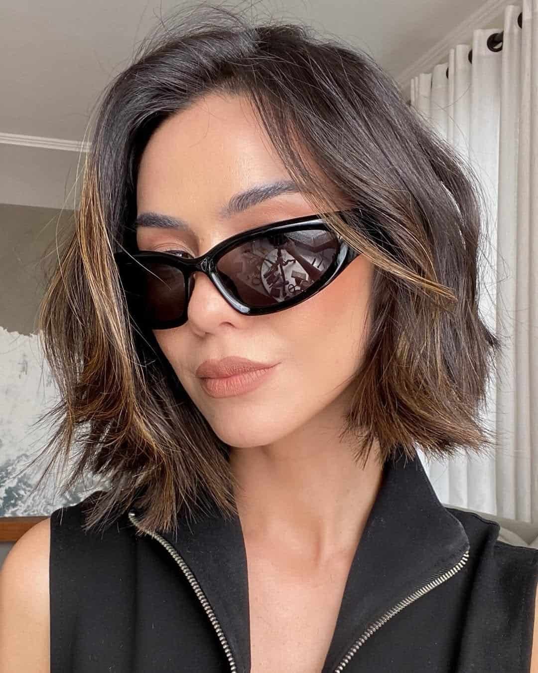 woman with a short textured dark brown bob and stylish black sunglasses