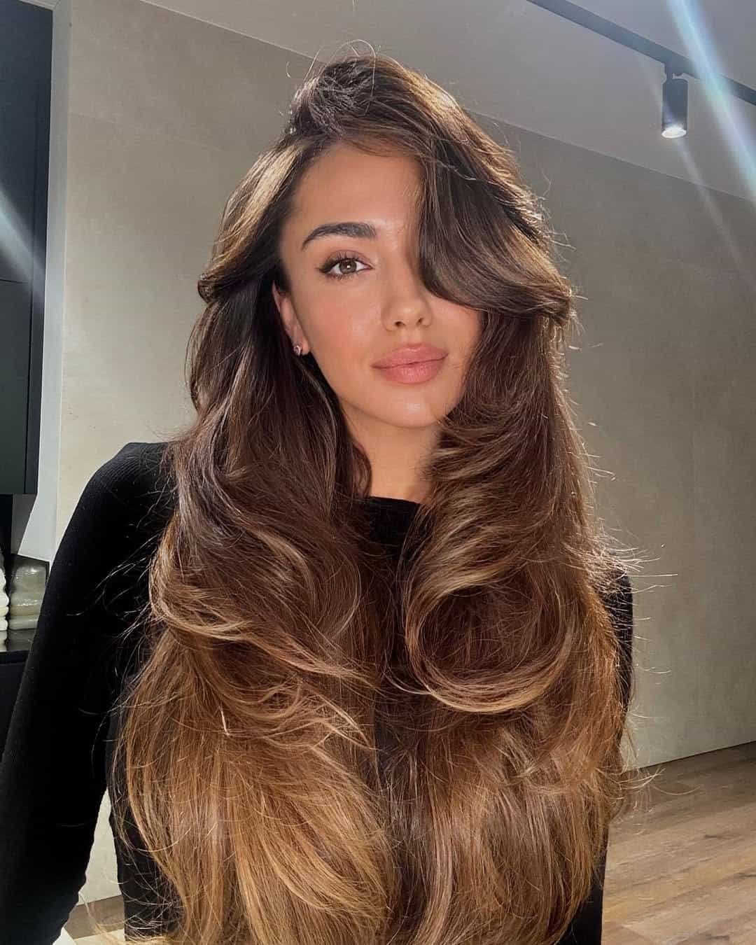 woman with long layered brunette hair and large bouncy curls