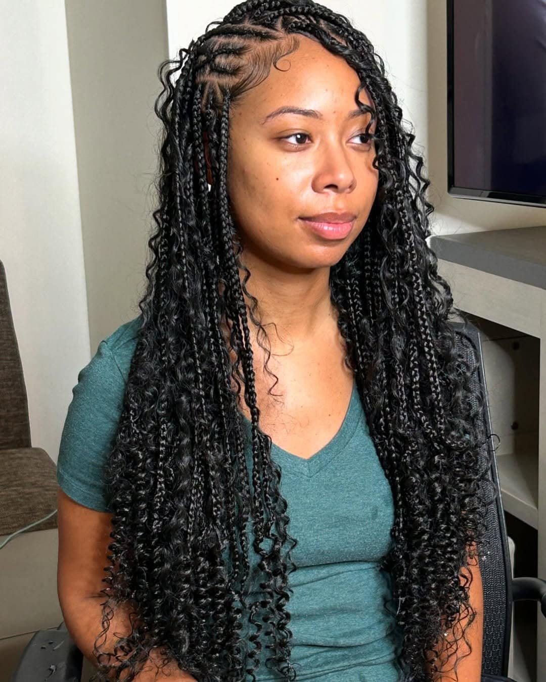 woman with long black micro braids and curly ends wearing green shirt