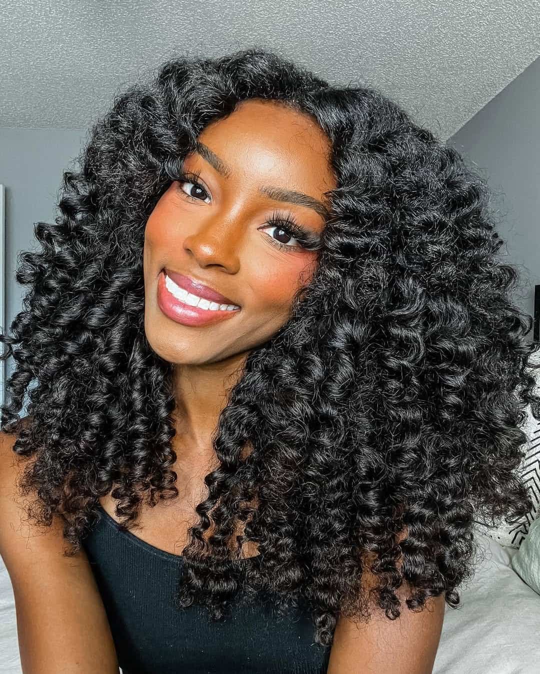 smiling woman with voluminous dark curly hair and defined ringlets