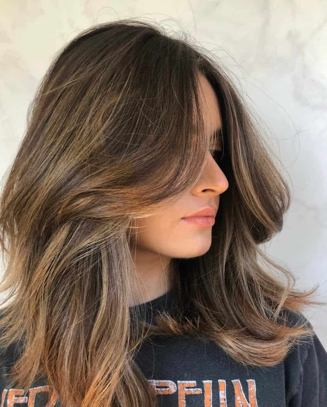 woman with medium length brown hair featuring layered curtain bangs and highlights