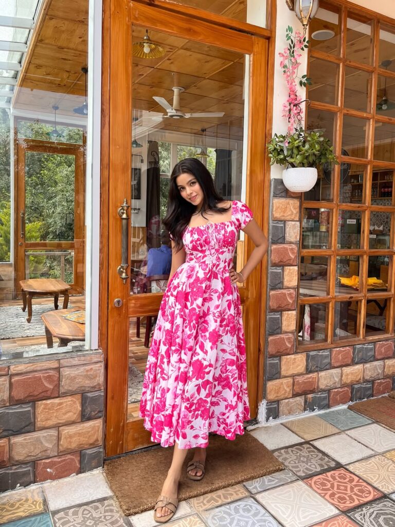 woman wearing a pink and white floral sundress standing in a doorway