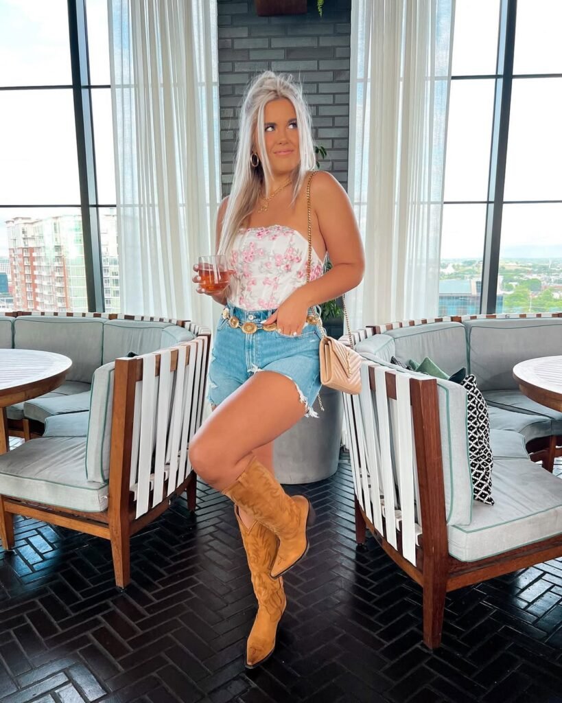 woman in floral corset top and denim shorts with cowboy boots at rooftop bar
