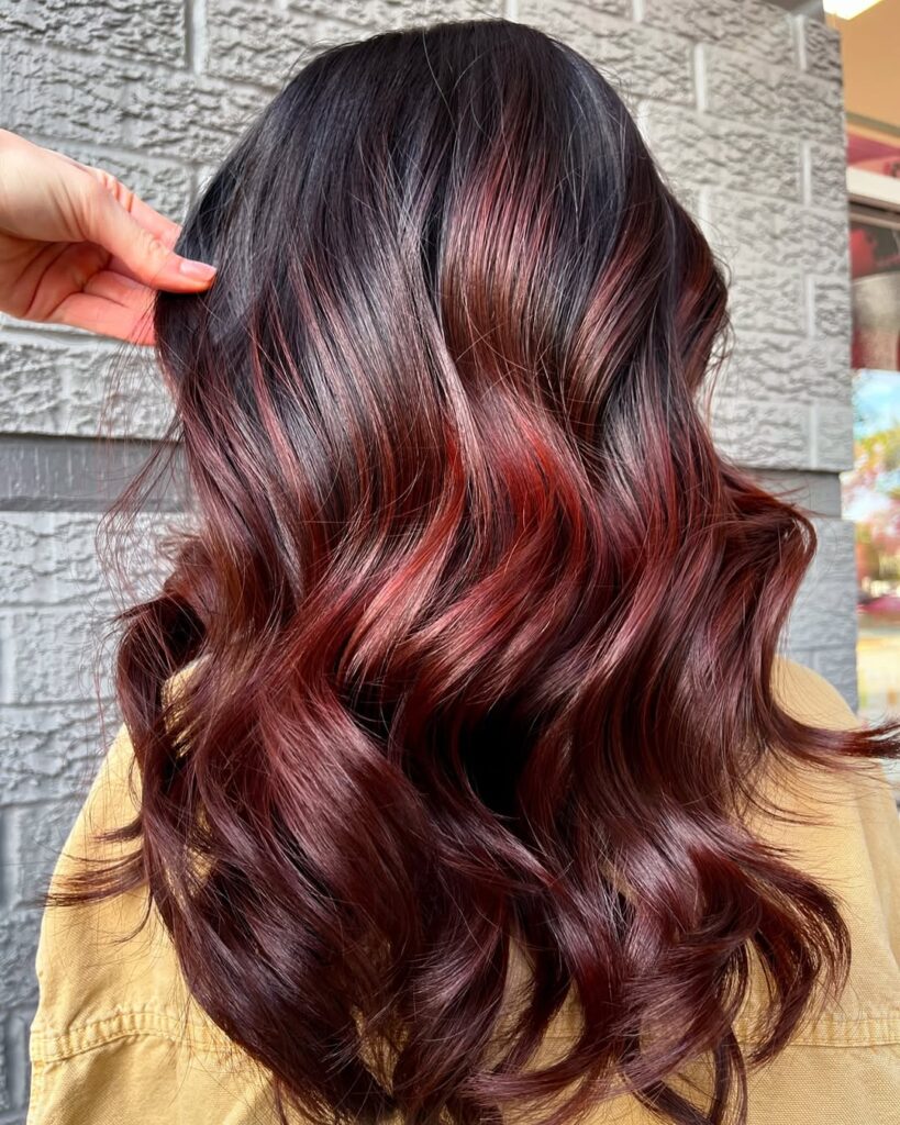 wavy cherry cola hair with deep red and burgundy highlights on a dark base