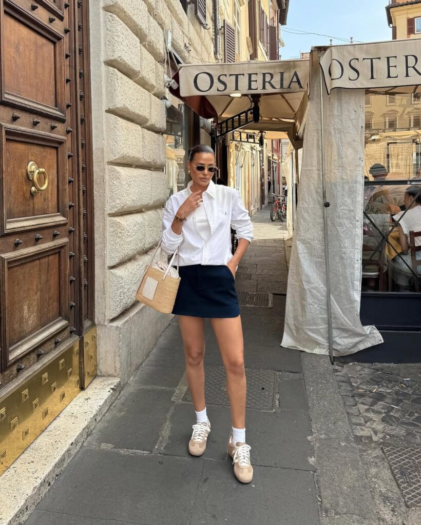 woman in a white shirt and navy skirt standing on a street in italy