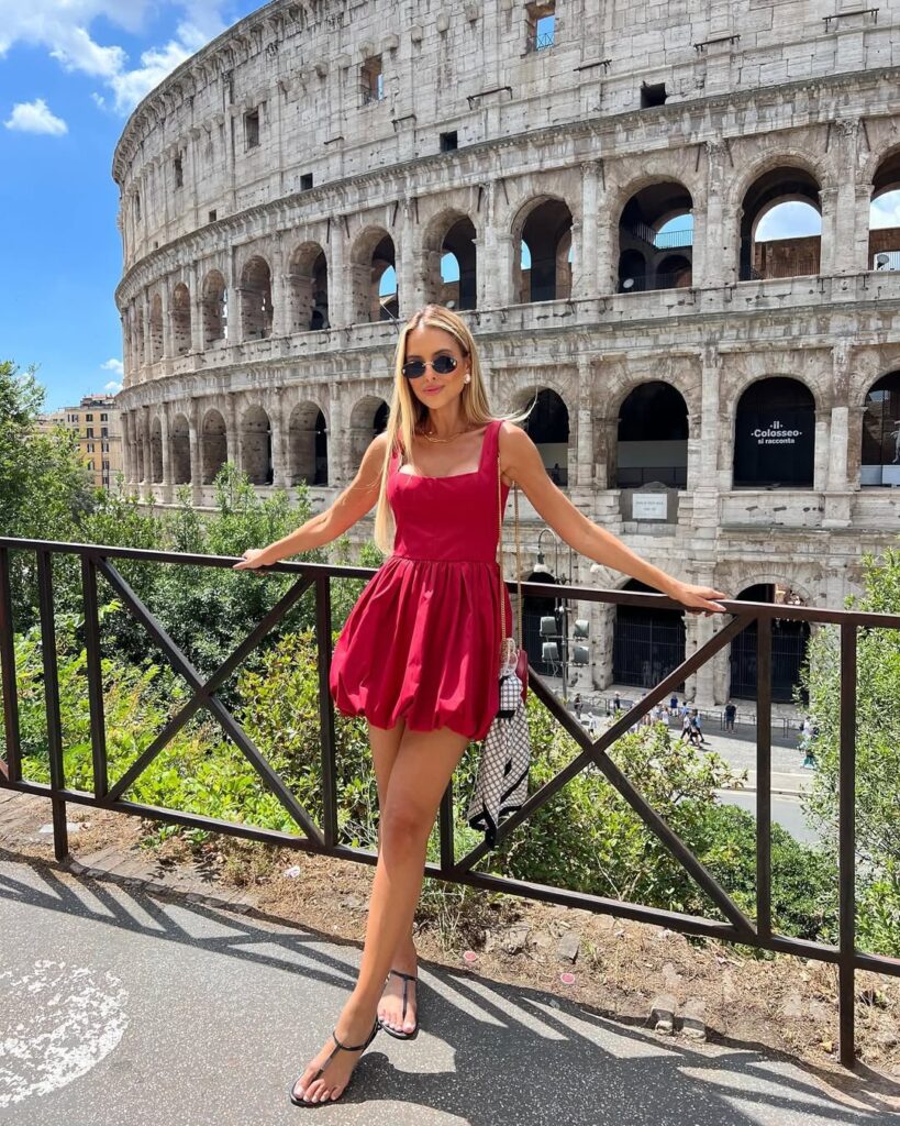woman in a red mini dress posing in front of the colosseum in rome