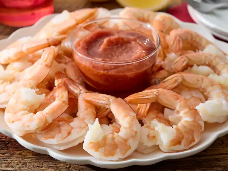 chilled shrimp cocktail served on a white platter with zesty red sauce