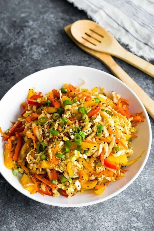 asian slaw with shredded cabbage, bell peppers, carrots, and scallions in a bowl.
