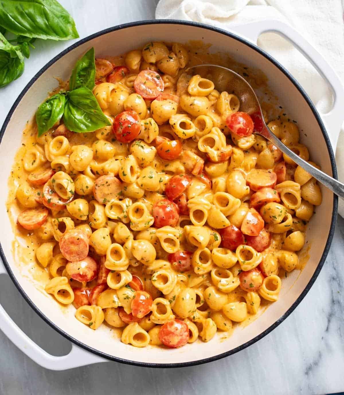 creamy cherry tomato pasta with fresh basil in a large white skillet.