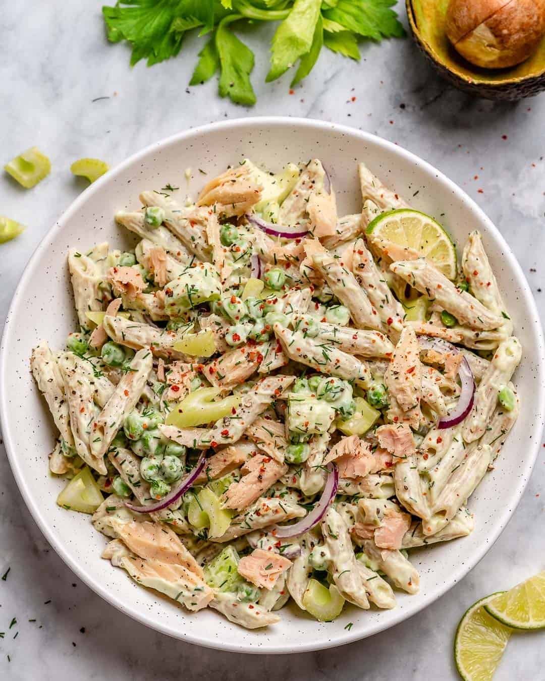 creamy tuna pasta salad with peas, red onions, and lime in a white bowl.