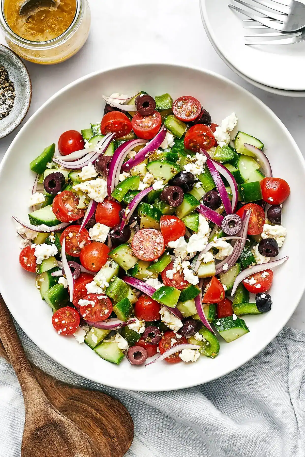 greek salad with chopped cucumbers, cherry tomatoes, red onions, olives, and crumbled feta cheese.